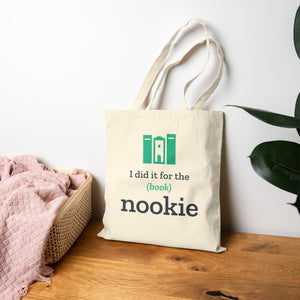 Natural book lover tote bag propped on a wood floor beside a bed